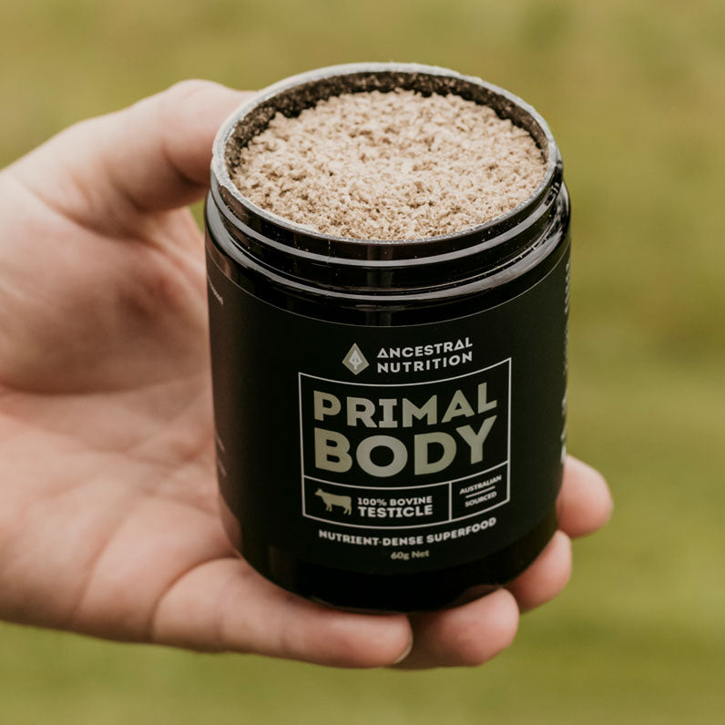 A hand holding a jar of Primal Body bulls testicle powder by Ancestral Nutrition