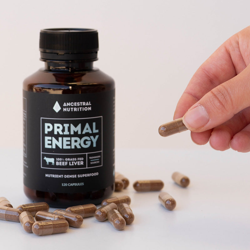 Image showing hand picking up a capsule of grass-fed beef liver supplements