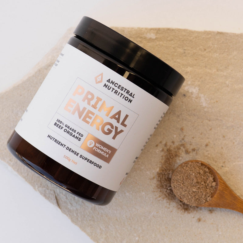 Jar of Ancestral Nutrition Primal Energy superfood with a wooden spoon of powder on a stone surface.